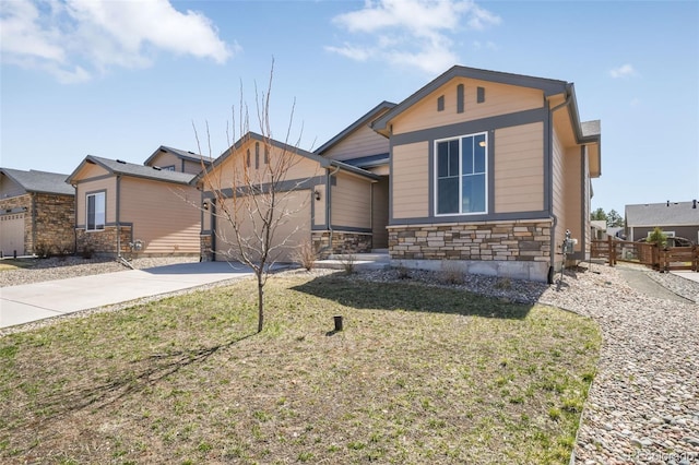 view of front of home with a garage, fence, stone siding, a front lawn, and concrete driveway