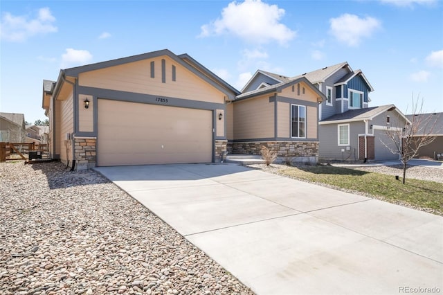 view of front of home with an attached garage, stone siding, and concrete driveway