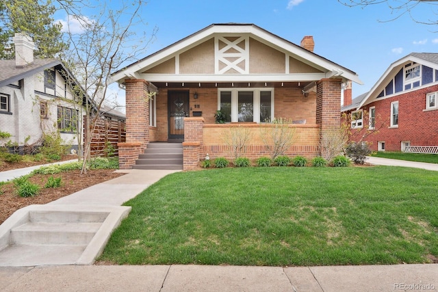 916 Adams St, Denver, CO 80206 - tudor house with brick siding, a front lawn, a porch, and a chimney