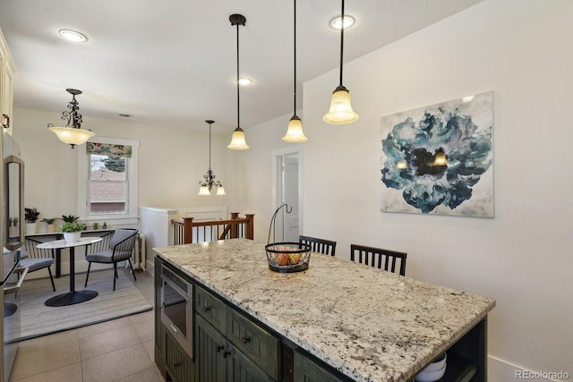 916 Adams St, Denver, CO 80206 - kitchen featuring stainless steel microwave, decorative light fixtures, light stone counters, a center island, and light tile patterned flooring