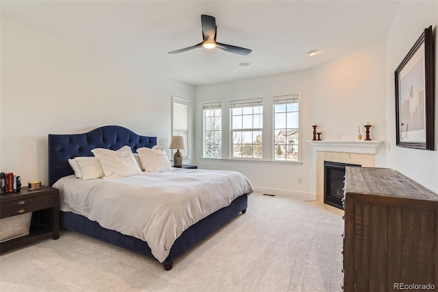 carpeted bedroom with a tile fireplace and ceiling fan