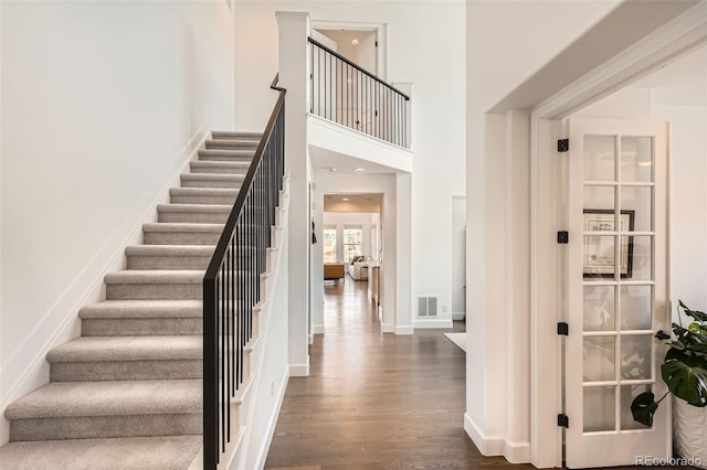 stairs with wood-type flooring and a high ceiling