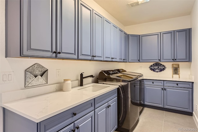 clothes washing area featuring cabinets, sink, light tile patterned floors, and independent washer and dryer