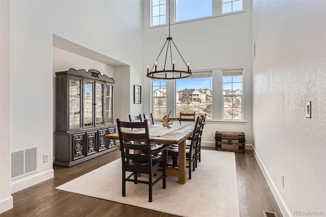 dining area featuring dark hardwood / wood-style flooring, a high ceiling, and a notable chandelier