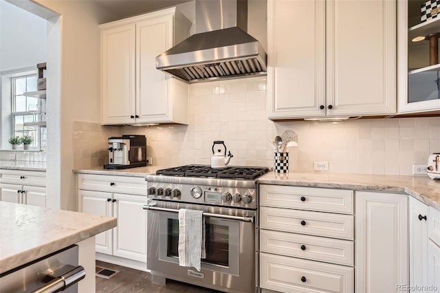 kitchen featuring white cabinetry, high end stainless steel range, extractor fan, and tasteful backsplash