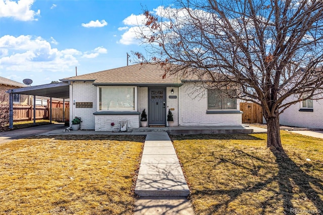 view of front of property featuring a front yard, fence, an attached carport, and brick siding