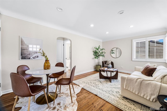 dining area featuring arched walkways, recessed lighting, wood finished floors, and baseboards