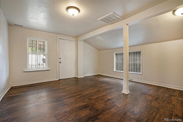 foyer with baseboards, a textured ceiling, visible vents, and wood finished floors