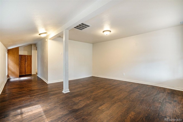 finished basement with dark wood-style floors, visible vents, and baseboards