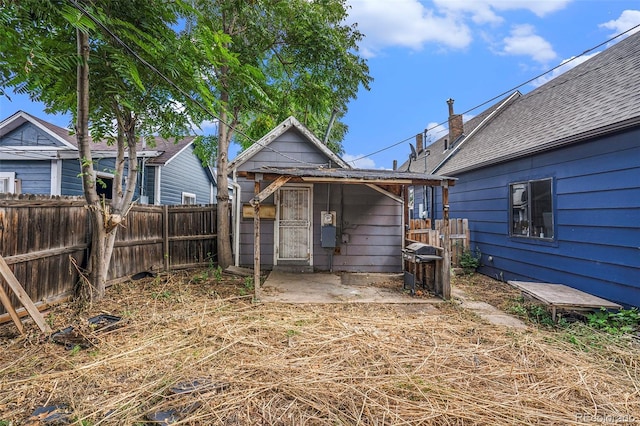 back of house with a fenced backyard, a patio, a shingled roof, and an outdoor structure