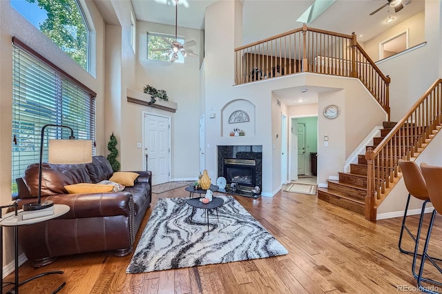 2417 S Racine Way, Aurora, CO 80014 - living room with a ceiling fan, a towering ceiling, stairs, wood-type flooring, and a fireplace