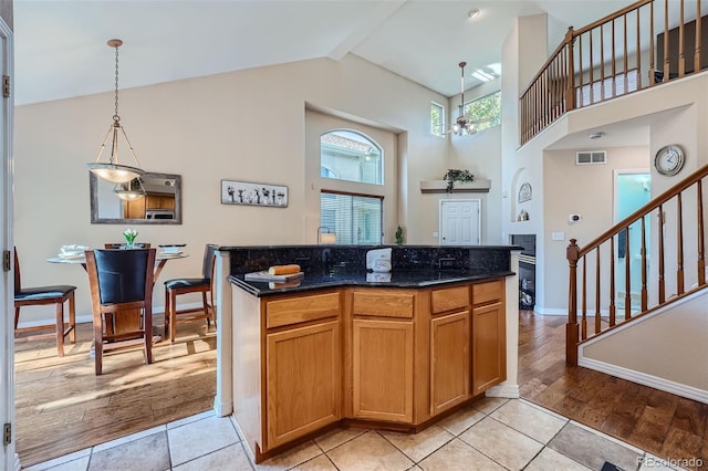 2417 S Racine Way, Aurora, CO 80014 - kitchen featuring pendant lighting, light tile patterned floors, a kitchen island, dark stone counters, and high vaulted ceiling