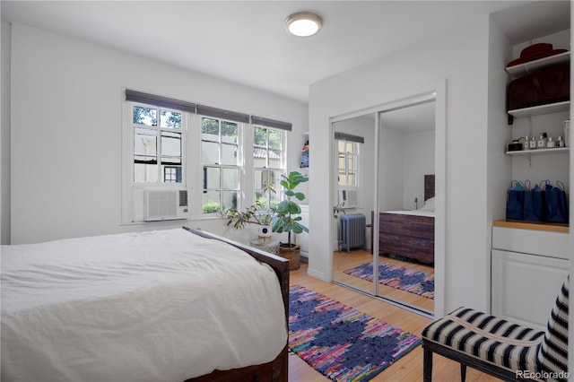 bedroom with cooling unit, wood-type flooring, radiator, and a closet