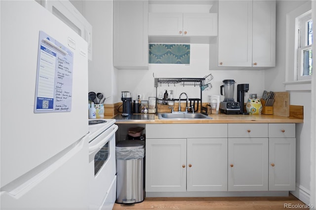 kitchen featuring white cabinets, refrigerator, sink, white electric range oven, and light hardwood / wood-style floors