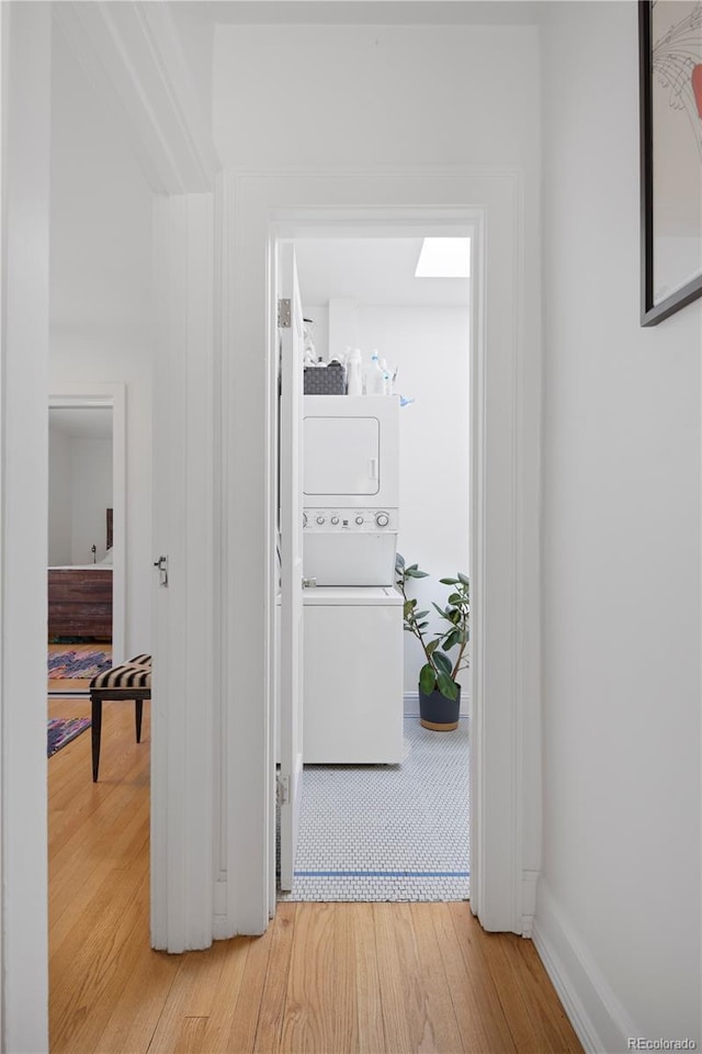 hall with stacked washer and dryer and hardwood / wood-style flooring