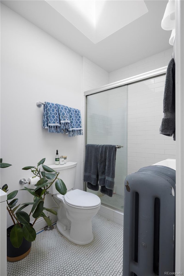 bathroom with tile patterned floors, toilet, and a shower with shower door