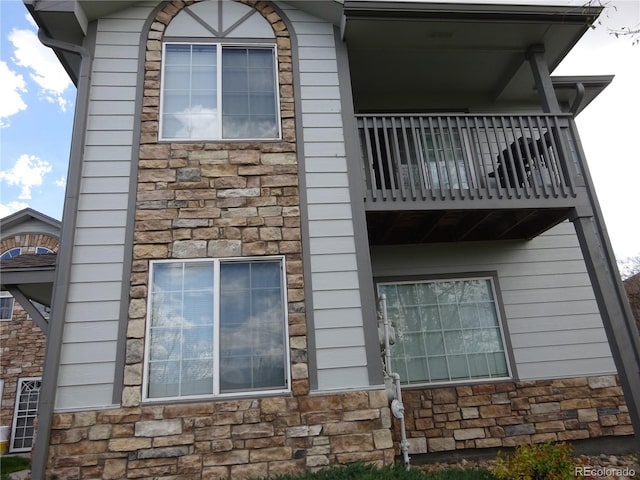 view of home's exterior with stone siding and a balcony