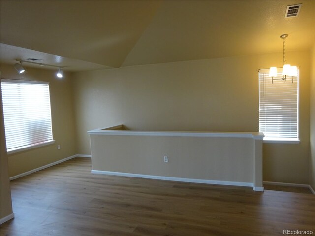 unfurnished room featuring wood finished floors, healthy amount of natural light, and rail lighting