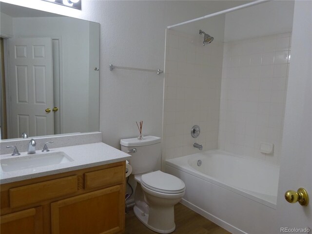 bathroom featuring toilet, vanity, wood finished floors, and washtub / shower combination