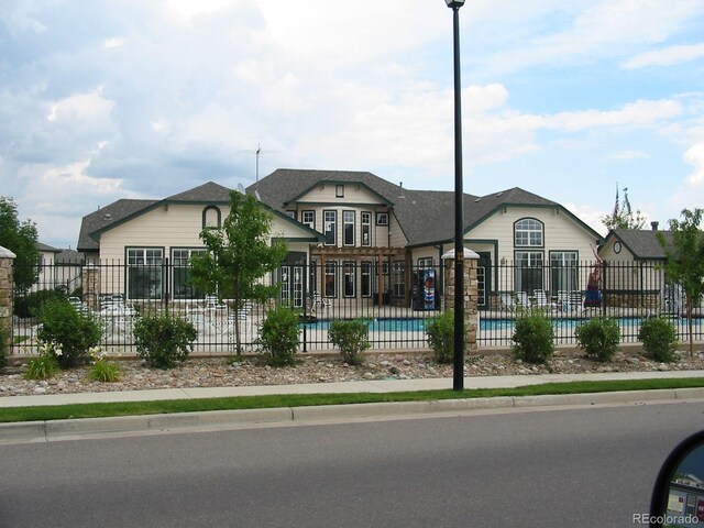 view of front of property featuring fence and a community pool