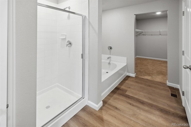 bathroom with hardwood / wood-style floors and independent shower and bath