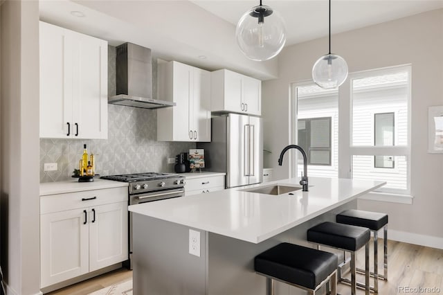 8280 E 36th Ave Unit 26, Denver, CO 80238 - kitchen featuring wall chimney range hood, light wood-style flooring, a sink, stainless steel appliances, and a center island with sink
