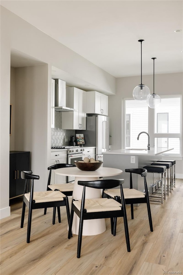 8280 E 36th Ave Unit 26, Denver, CO 80238 - kitchen featuring wall chimney range hood, white cabinetry, light wood-style flooring, and healthy amount of natural light
