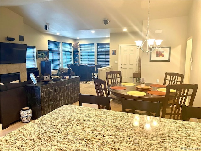 dining space with a fireplace, a chandelier, recessed lighting, and wood finished floors