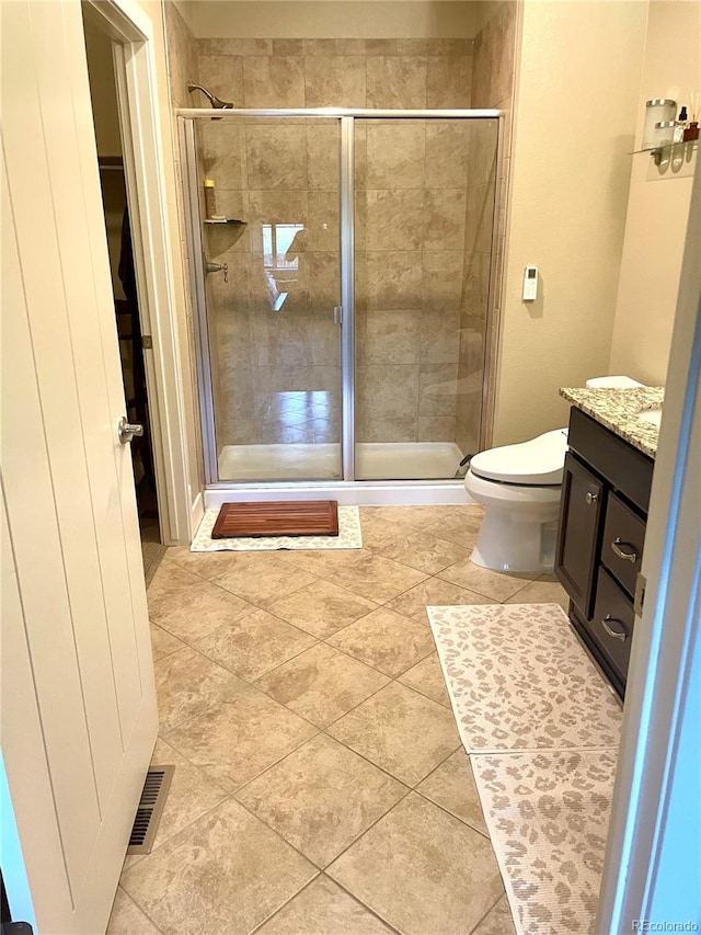 full bath featuring toilet, vanity, visible vents, a stall shower, and tile patterned flooring