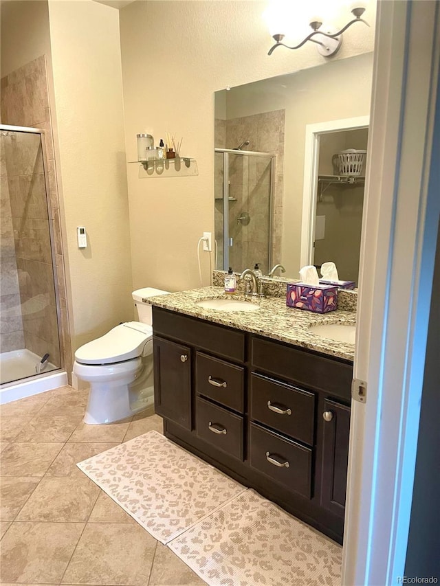 bathroom with a stall shower, a sink, tile patterned flooring, double vanity, and a walk in closet