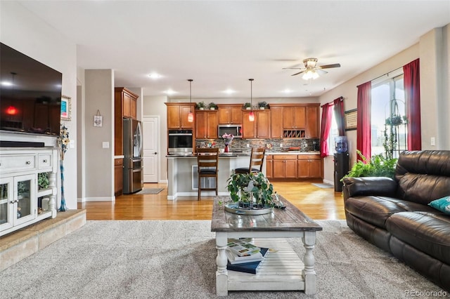 living room with a ceiling fan, light wood-type flooring, and baseboards