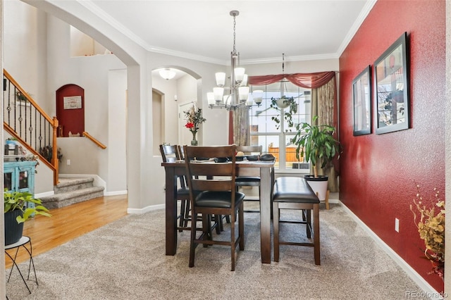 carpeted dining room featuring ornamental molding, arched walkways, stairway, and baseboards