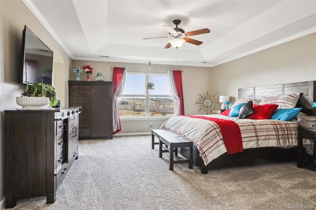 bedroom with light carpet, a tray ceiling, a ceiling fan, and ornamental molding