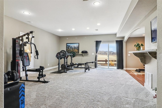 exercise area with arched walkways, recessed lighting, carpet floors, visible vents, and baseboards