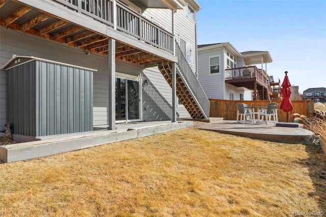 rear view of property featuring a patio area, fence, a lawn, and stairs