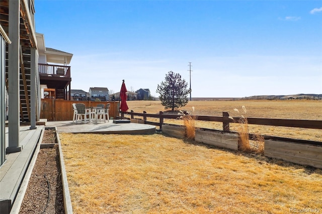 view of yard featuring a rural view, a patio area, and a fenced backyard