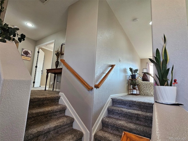 staircase featuring baseboards, carpet flooring, and a textured wall