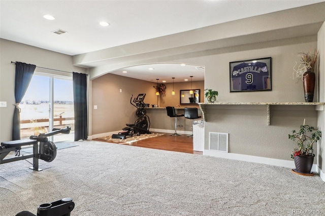 workout area featuring carpet flooring, visible vents, baseboards, and arched walkways