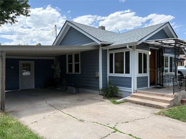 1337 Valentia St, Denver, CO 80220 - view of front of home with roof with shingles, an attached carport, driveway, and a chimney
