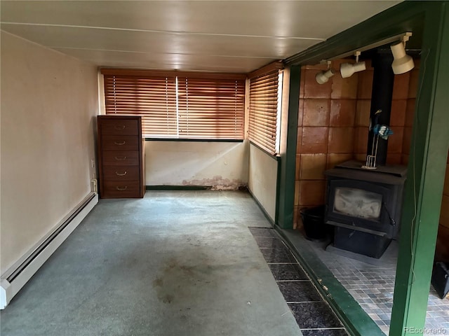 1337 Valentia St, Denver, CO 80220 - interior space featuring a baseboard heating unit, a wood stove, and unfinished concrete floors
