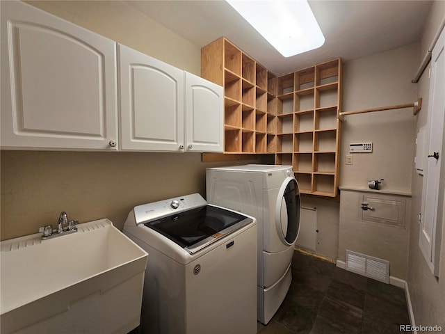 clothes washing area featuring washer and dryer, sink, and cabinets