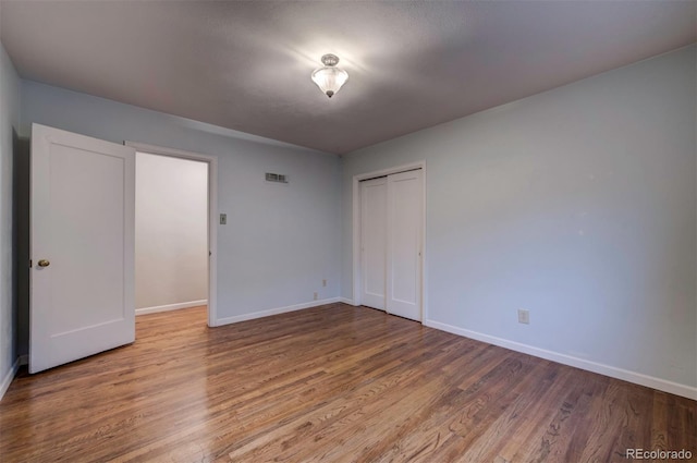 unfurnished bedroom featuring wood-type flooring and a closet