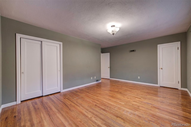 unfurnished bedroom with a textured ceiling and light wood-type flooring