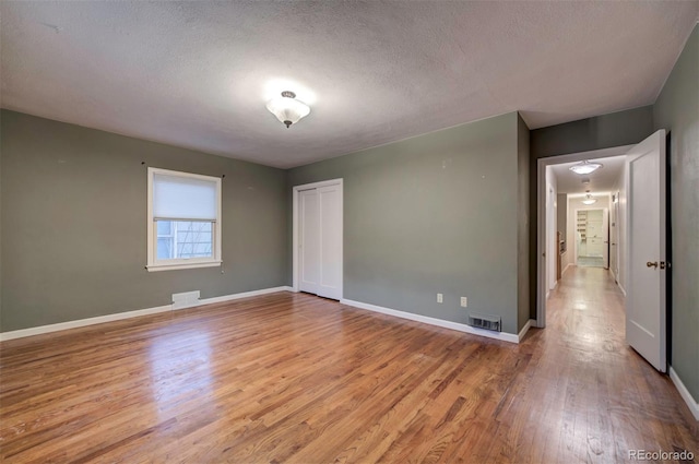 unfurnished room featuring light hardwood / wood-style floors and a textured ceiling