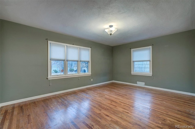 spare room with light hardwood / wood-style flooring and a textured ceiling