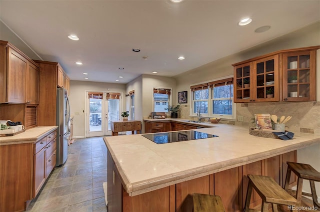 kitchen featuring sink, stainless steel fridge, backsplash, a kitchen bar, and kitchen peninsula