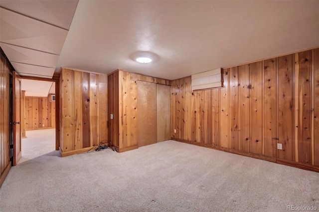 basement featuring light colored carpet and wood walls