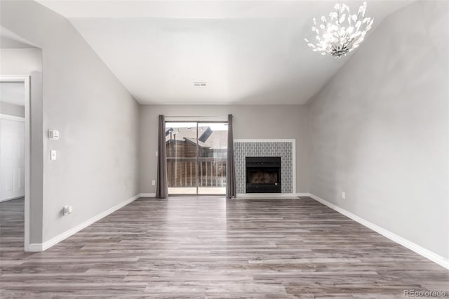 2267 S Buckley Rd Unit 202, Aurora, CO 80013 - unfurnished living room featuring wood finished floors, a chandelier, a tile fireplace, and lofted ceiling