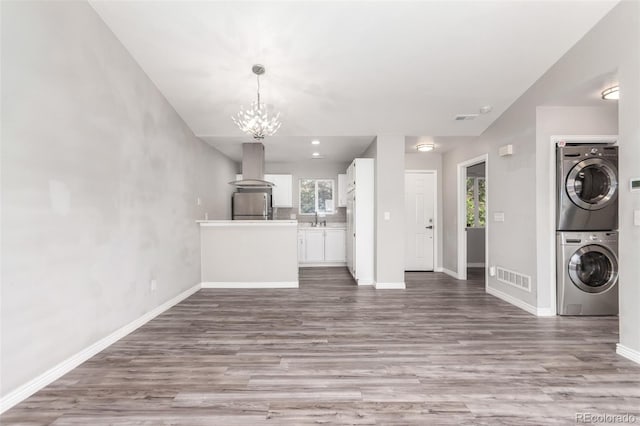2267 S Buckley Rd Unit 202, Aurora, CO 80013 - unfurnished living room with stacked washing machine and dryer, wood finished floors, and a chandelier