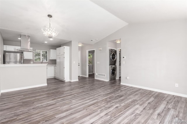 2267 S Buckley Rd Unit 202, Aurora, CO 80013 - unfurnished living room with stacked washer / dryer, light wood-style flooring, a chandelier, and vaulted ceiling